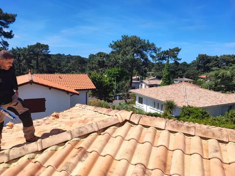 Couvreur posant les tuiles du faîtage